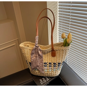 Detail of beige straw tote bag with colorful openwork weave and brown leather handles