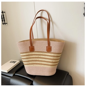 Detail of multi-color woven straw tote bag featuring pink stripes and brown leather handles