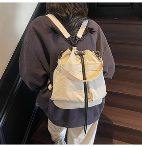 Detailweergave van een crème canvas rugzak met trekkoord en verstelbare riemen op model