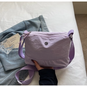 Detail of lavender nylon crossbody bag with multi-zipper layers and metallic logo
