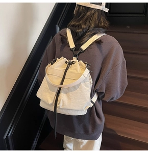 Detail van de beige bucket-rugzak met trekkoord en brede banden op een model