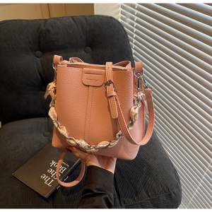 Detail of pink pebble leather bucket bag with floral silk scarf wrapped on the handle