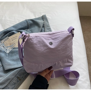 Close-up of lilac nylon crossbody bag with textured fabric and dual zipper detail