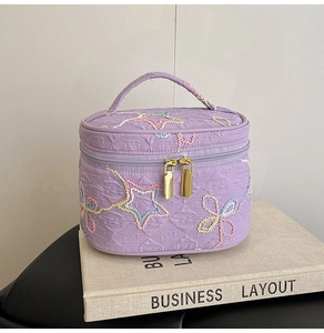 Detail der lila gesteppten Kosmetiktasche mit Sternstickerei und Goldreißverschluss