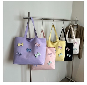 Row of colorful canvas tote bags with polka dot bows hanging on a metal rack