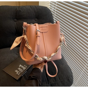 Detail of pink bucket bag with lychee texture leather and silk scarf wrapped chain strap