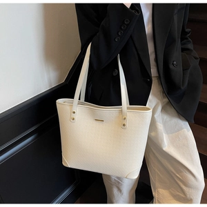 Detailed macro of off-white tote bag showing diagonal embossed texture and gold hardware