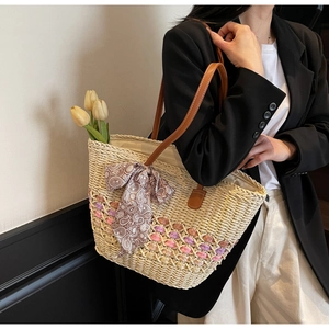 Detail of straw tote bag with colorful weaving accents and decorative paisley silk scarf