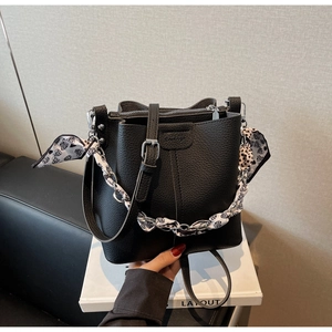 Detailed shot of black litchi pattern bucket bag with heart-printed silk scarf handle