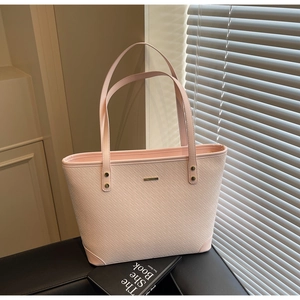 Detailed close-up of light pink woven texture and gold hardware on a structured tote bag