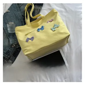 Detail of yellow canvas tote bag with five colorful polka dot bow decorations