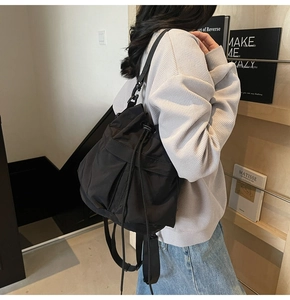 Detailweergave van de zwarte nylon emmertas met trekkoord gedragen als casual crossbodytas