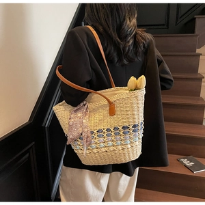 Detail of woven straw tote bag with floral crochet accents and leather straps