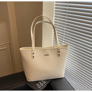 Close-up of cream embossed tote bag with fine twill texture and metal accent detail