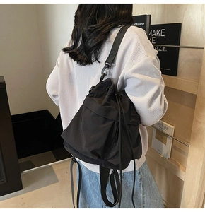 Detail achteraanzicht van model met zwarte nylon bucket bag met trekkoord sluiting