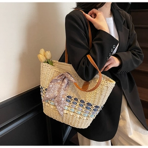 Detail of woven straw tote bag with colorful wave patterns and brown leather handles
