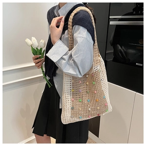 Detail of hollow woven mesh tote bag featuring colorful pearls and contrast stitching
