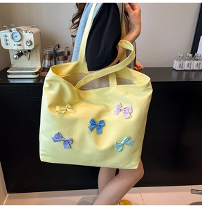 Detailed close-up of yellow canvas tote bag featuring colorful polka dot bow decorations