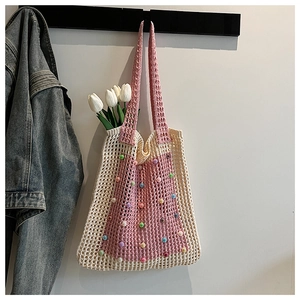 Detail of bohemian crochet tote bag featuring colorful bead accents and pink woven trim