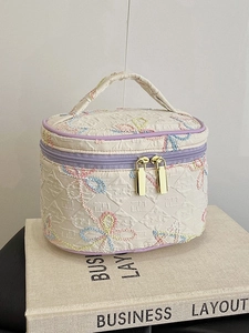 Gesteppte cremefarbene Kosmetiktasche mit Schmetterlingsstickerei und lila Paspel