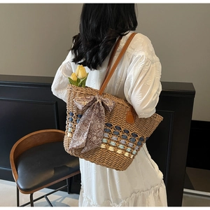 Detail of straw tote bag featuring blue woven base accents and a vintage bow decoration