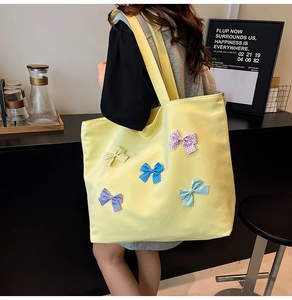 Close-up of yellow canvas tote bag with five colorful polka dot bows for a sweet style