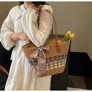 Detail of woven straw tote bag with blue gradient base and vintage pattern silk scarf