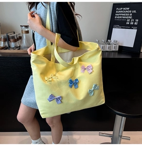 Detail of yellow canvas tote bag with colorful polka dot bows and wide shoulder straps
