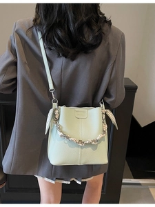 Mint green lychee texture bucket bag with silk scarf handle and leather strap worn by model