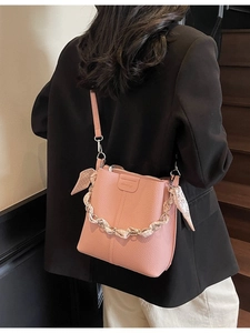 Pink lychee grain leather bucket bag with silk scarf detail on a model in a stair setting