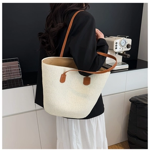 Primer plano de un bolso tote tejido beige con correas marrones en un entorno moderno