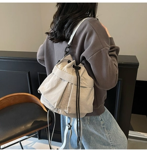 Detail van gebroken witte rugzak met trekkoord en verstelbare zwarte metalen gespen
