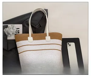Détail du cabas de plage tissé à rayures avec poignées en cuir blanc et texture paille