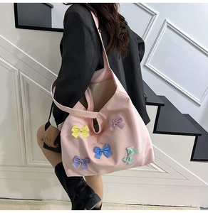 Detail of pink plaid tote bag featuring colorful polka dot bows and long shoulder straps