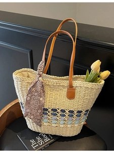 Straw beach tote bag with brown leather handles and decorative silk scarf detail