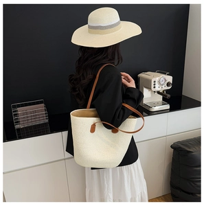 Detalle del bolso tote de paja tejido a mano con asas de cuero marrón y textura beige