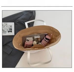 Vue détaillée de l'intérieur du grand sac fourre-tout en paille beige avec ses accessoires