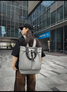 Sac à dos tote en nylon gris sur mannequin devant un bâtiment moderne en ville