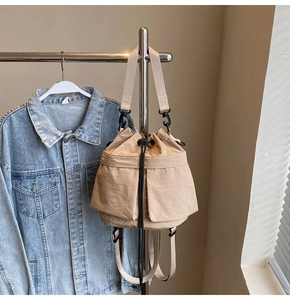 Detail van de beige bucket bag met trekkoord, zijzakken en duurzame geweven handvatten