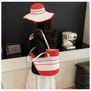 Détail du sac cabas en paille rayé rouge et blanc avec chapeau de soleil assorti sur modèle