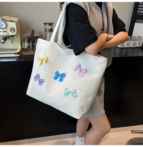 Detail of white canvas tote bag with multi-colored polka dot bows in a cafe setting