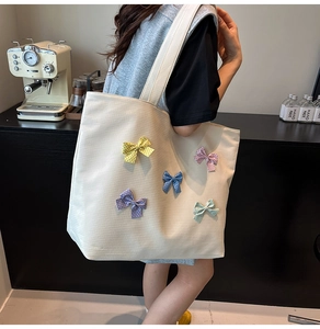 Detail of cream canvas tote bag with colorful polka dot bows and subtle grid texture