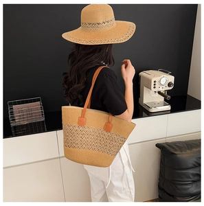 Detalle del bolso tote de paja tejida y sombrero con asas de cuero de color marrón