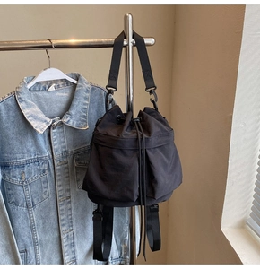Detail van zwarte bucket bag met trekkoord, utility-zakken en verstelbare riem