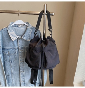 Detail van zwarte bucket bag met trekkoordsluiting en verstelbare nylon riemen