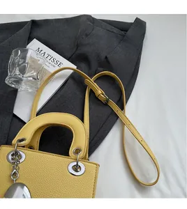 Detailed macro view of the yellow lychee grain leather finish and silver metal charms