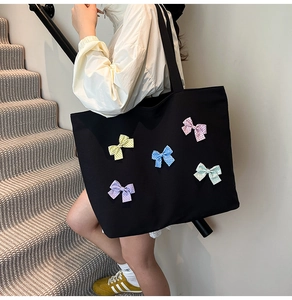 Close-up of black quilted tote bag featuring colorful polka dot bows on a canvas texture