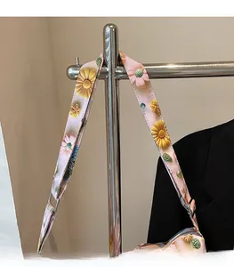 Detail view of pink canvas shoulder strap with yellow daisy print and metal hooks