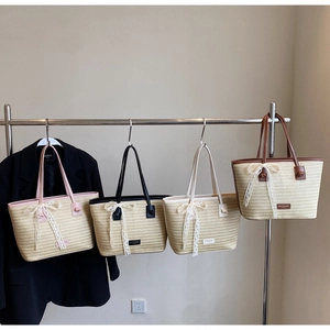 Détail de sacs cabas en paille tissée avec nœuds en dentelle en rose, noir et crème