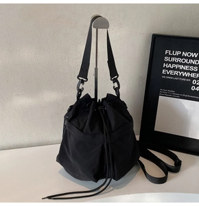 Detail van zwarte nylon bucket bag met trekkoordsluiting en functionele voorzakken